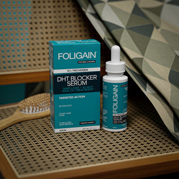 Botol dan kotak serum penyekat DHT FOLIGAIN di atas tempat duduk kerusi beranyam.