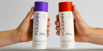 Tangan memegang perapi TRIOXIDIL FOLIGAIN untuk wanita dan lelaki dengan penutup ungu dan jingga.