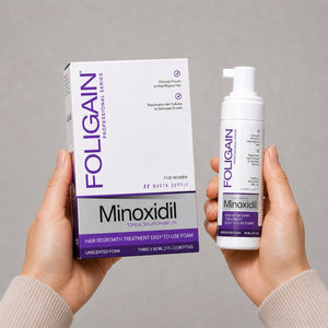 Tangan memegang kotak dan botol buih sapuan minoksidil 5% FOLIGAIN untuk wanita.