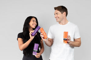 Wanita dan lelaki memegang botol penjagaan rambut FOLIGAIN berwarna ungu dan jingga.