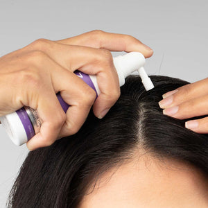 Wanita menyapu rawatan sapuan FOLIGAIN TRIOXIDIL sepanjang belahan rambutnya